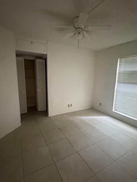 spare room with ceiling fan and light tile patterned floors