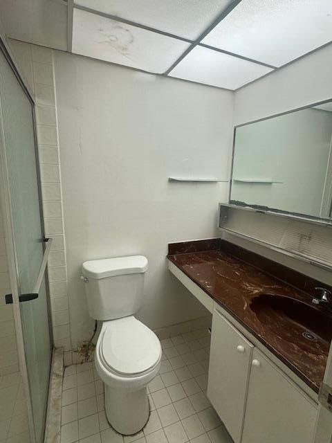 bathroom with vanity, tile patterned floors, toilet, and an enclosed shower