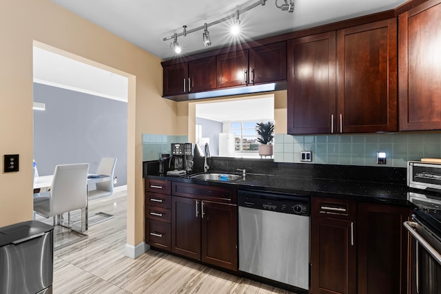 kitchen featuring sink, stainless steel appliances, backsplash, dark stone counters, and track lighting