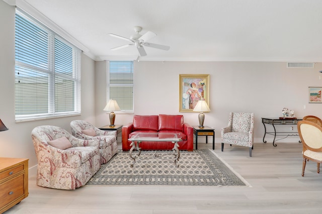 living room featuring ceiling fan, ornamental molding, and light hardwood / wood-style flooring