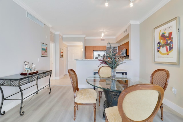 dining room with track lighting, light hardwood / wood-style floors, and crown molding