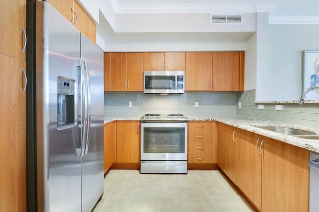 kitchen featuring backsplash, appliances with stainless steel finishes, sink, and light stone countertops