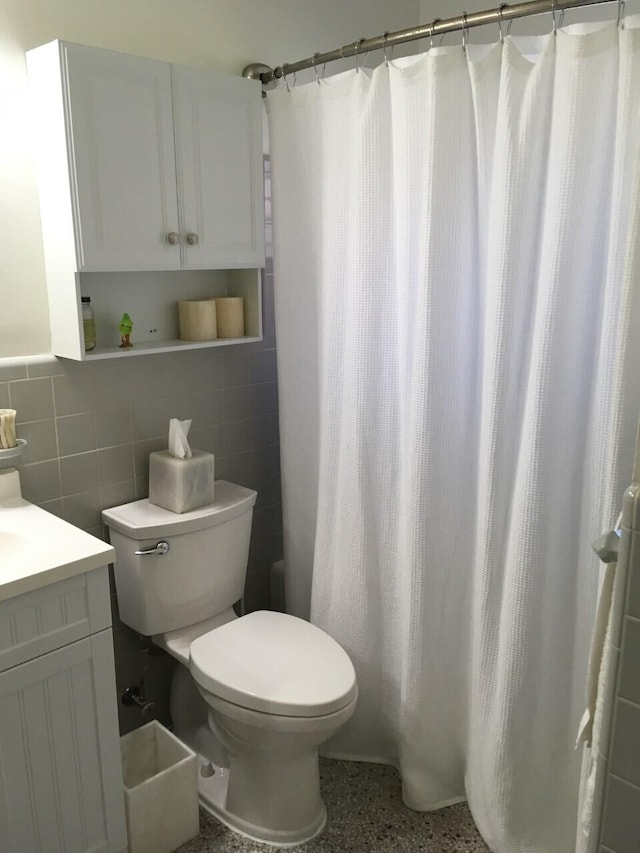 bathroom featuring toilet, curtained shower, vanity, and tile walls