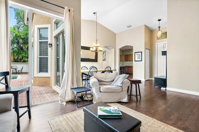 living room featuring dark wood-type flooring, lofted ceiling, and a notable chandelier