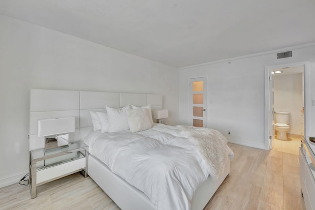 bedroom featuring connected bathroom and light hardwood / wood-style floors