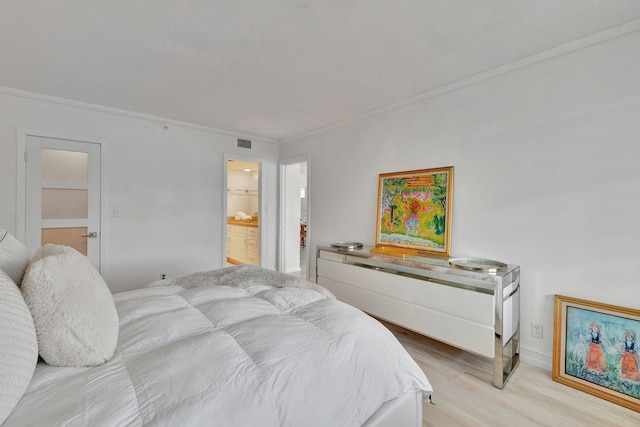 bedroom featuring light hardwood / wood-style floors, ensuite bath, and crown molding