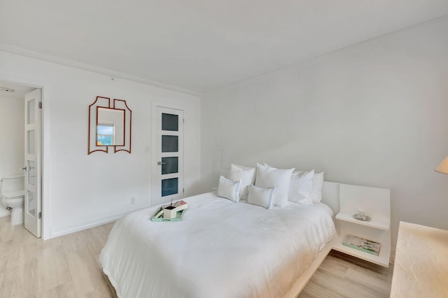 bedroom featuring connected bathroom and light hardwood / wood-style flooring