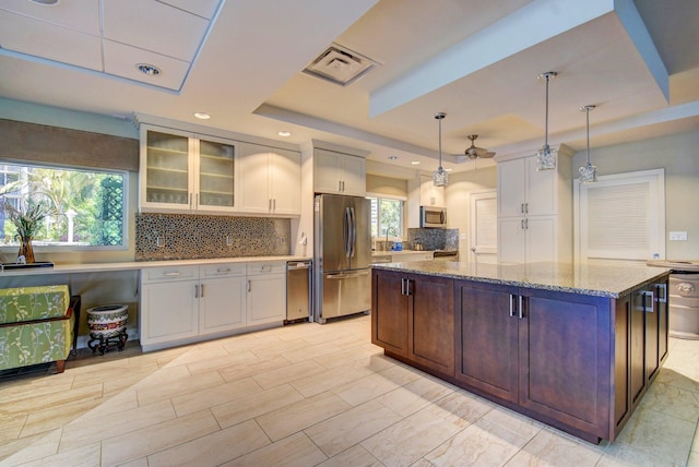 kitchen featuring pendant lighting, a tray ceiling, dark brown cabinets, white cabinetry, and stainless steel appliances