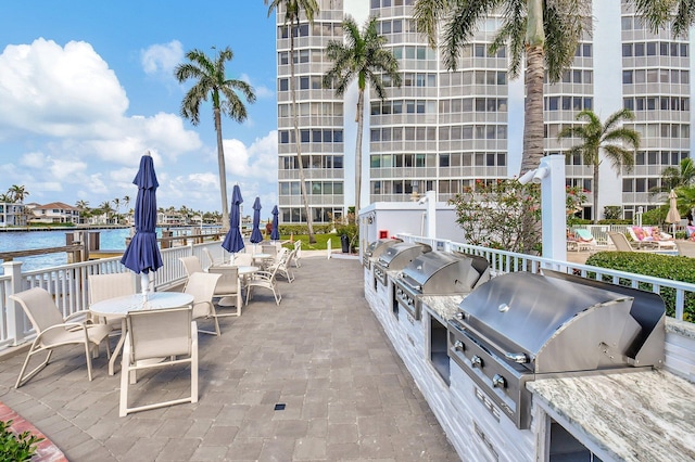 view of patio / terrace featuring a water view, area for grilling, and exterior kitchen