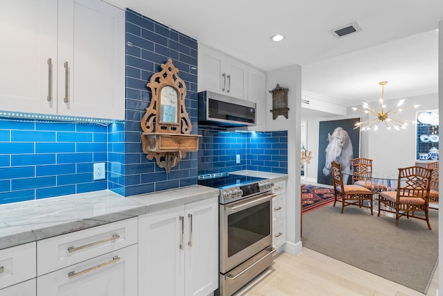 kitchen with tasteful backsplash, light stone counters, stainless steel appliances, white cabinetry, and light hardwood / wood-style floors