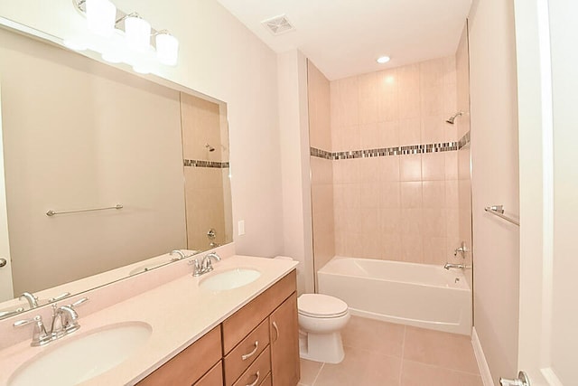 full bathroom featuring tile patterned flooring, tiled shower / bath combo, toilet, and vanity