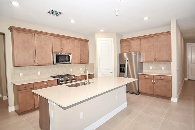 kitchen featuring sink, a kitchen island with sink, stainless steel appliances, decorative backsplash, and light tile patterned floors