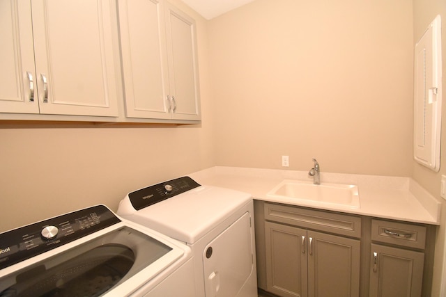 laundry room with cabinets, washing machine and dryer, and sink