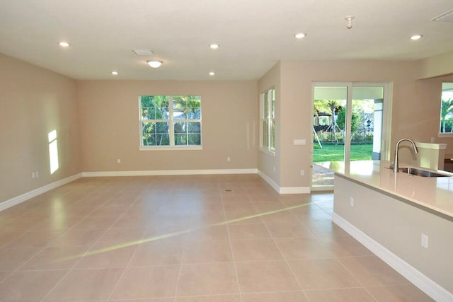 unfurnished living room with plenty of natural light, light tile patterned floors, and sink