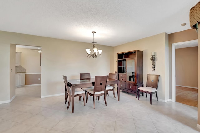 tiled dining area with a chandelier and a textured ceiling