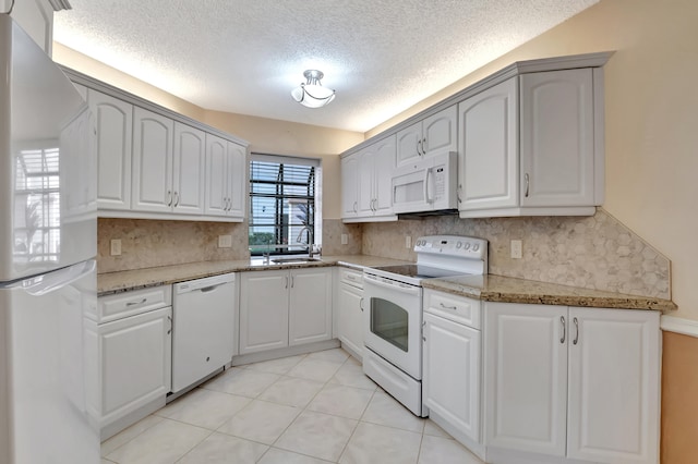 kitchen with backsplash, a textured ceiling, white appliances, stone countertops, and white cabinetry