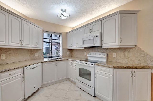 kitchen featuring white appliances, vaulted ceiling, a textured ceiling, light stone counters, and white cabinetry