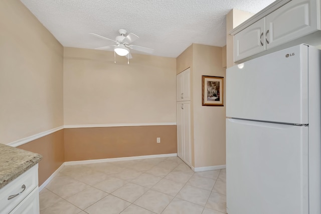 kitchen featuring white cabinetry, ceiling fan, white refrigerator, a textured ceiling, and light tile patterned floors