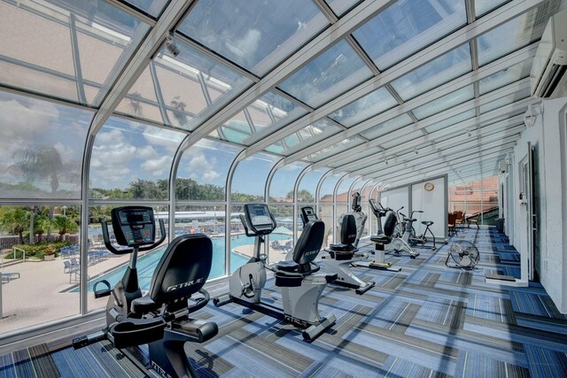 exercise room featuring carpet flooring, expansive windows, and a wall mounted AC