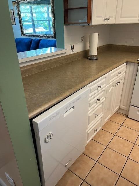 kitchen featuring white cabinets, light tile patterned flooring, backsplash, and white appliances