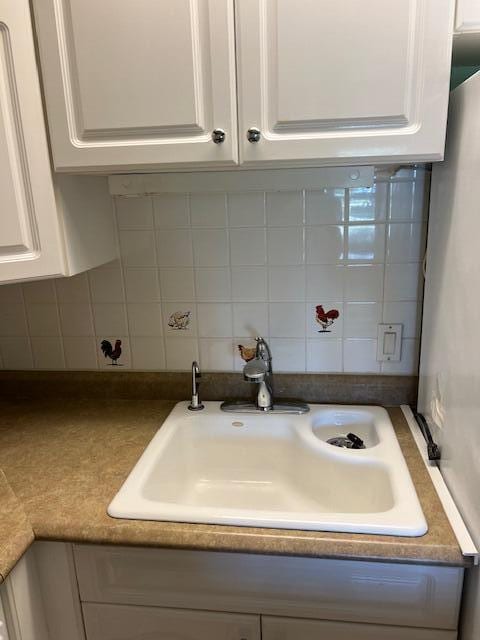 interior details featuring white cabinetry, tasteful backsplash, and sink