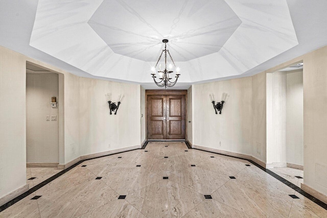 entryway with a tray ceiling and an inviting chandelier