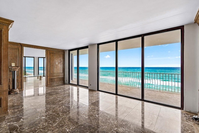 unfurnished room featuring a wall of windows and a water view