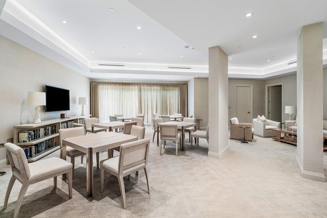 carpeted dining space with a raised ceiling