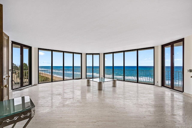 unfurnished living room with floor to ceiling windows, a water view, and a wealth of natural light