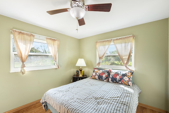 bedroom with hardwood / wood-style flooring, multiple windows, and ceiling fan