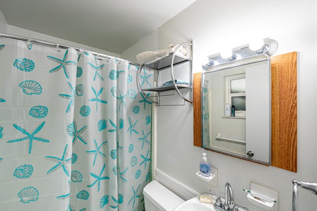 bathroom featuring sink, a shower with shower curtain, and toilet