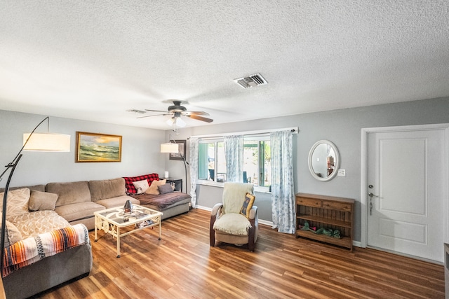 living room with ceiling fan, a textured ceiling, and hardwood / wood-style floors