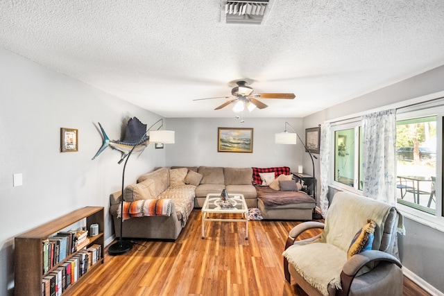 living room featuring light hardwood / wood-style floors, a textured ceiling, and ceiling fan