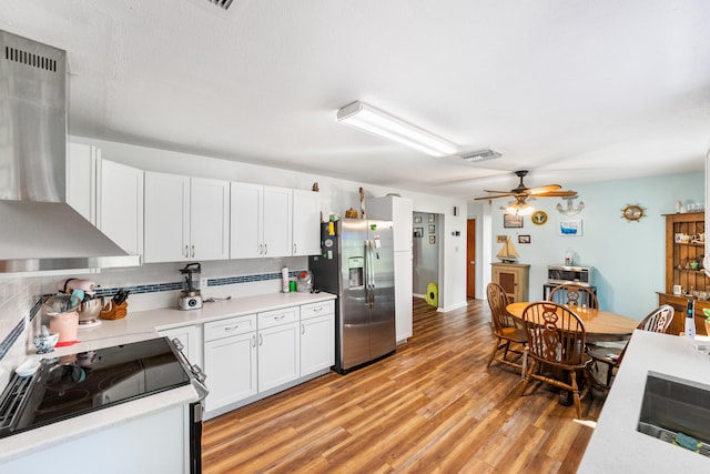 kitchen with stainless steel fridge, white cabinets, electric range, backsplash, and light wood-type flooring