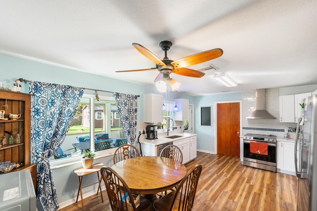 dining space with light hardwood / wood-style floors, a textured ceiling, sink, and ceiling fan