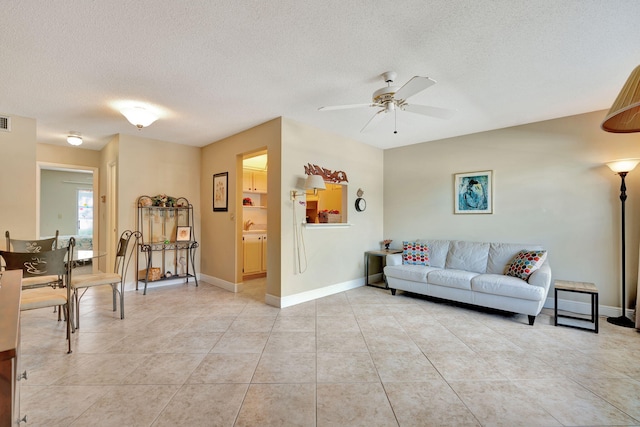 living room featuring ceiling fan, a textured ceiling, and light tile patterned floors