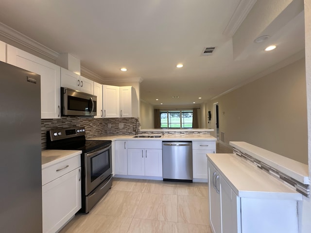 kitchen featuring appliances with stainless steel finishes, sink, kitchen peninsula, white cabinetry, and ornamental molding