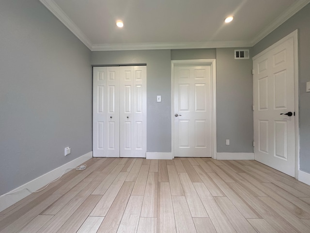 unfurnished bedroom with light hardwood / wood-style floors, crown molding, and multiple closets