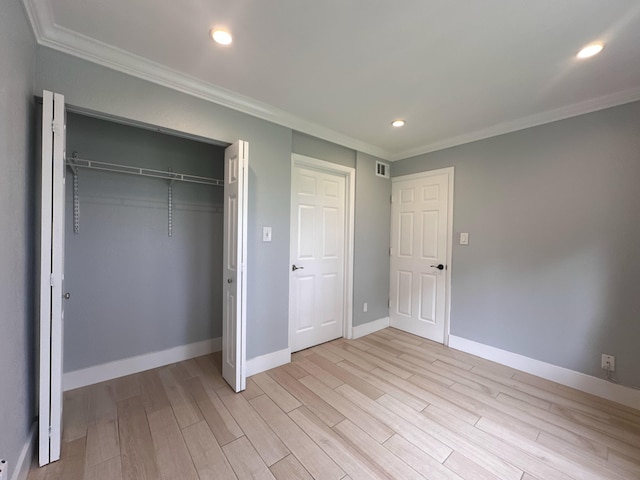 unfurnished bedroom featuring a closet, crown molding, and light wood-type flooring