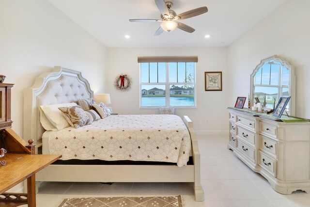 bedroom with a water view, ceiling fan, light tile patterned flooring, and multiple windows