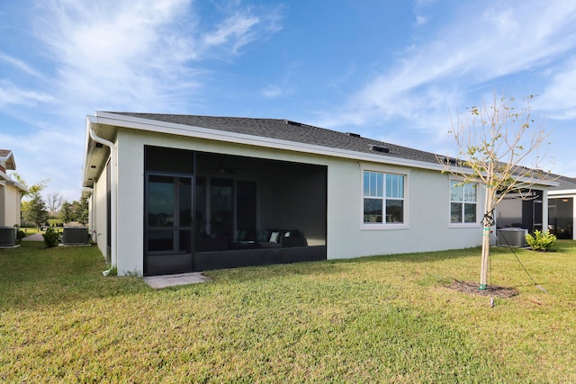 back of property with central air condition unit, a sunroom, and a lawn