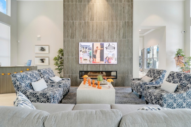 living room featuring tile walls, a high ceiling, and a large fireplace