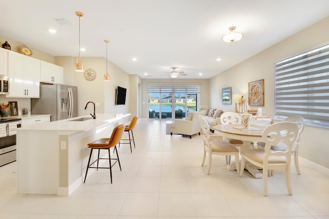 tiled dining area featuring ceiling fan and sink