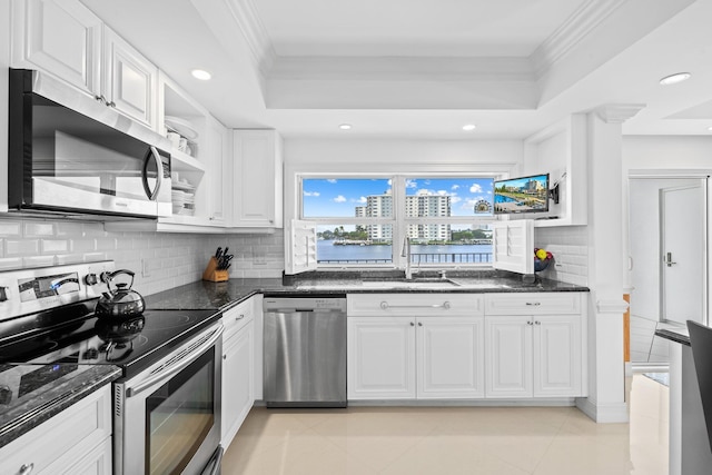 kitchen featuring dark stone counters, white cabinetry, appliances with stainless steel finishes, and crown molding