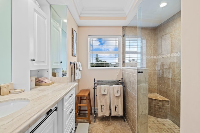 bathroom featuring tile patterned floors, a tile shower, crown molding, vanity, and a raised ceiling