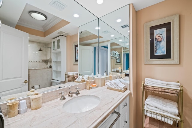 bathroom featuring tiled shower, vanity, toilet, and ornamental molding