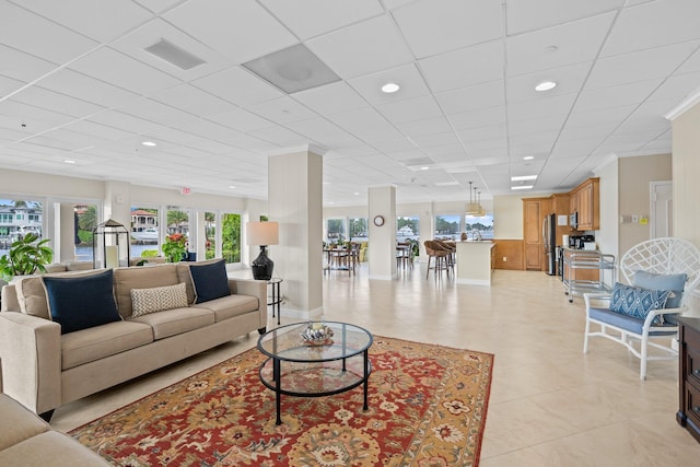 living room featuring light tile patterned flooring, french doors, and a drop ceiling