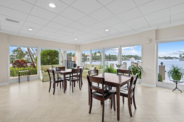 dining room featuring a wealth of natural light, a water view, and light tile patterned floors