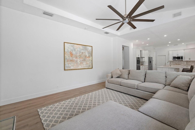 living room with sink, ceiling fan, and light hardwood / wood-style flooring