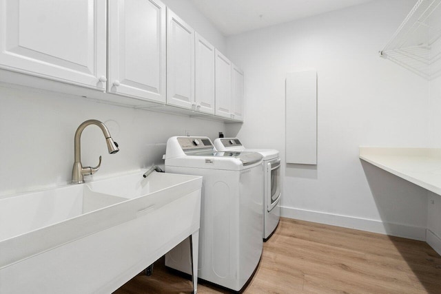 laundry room featuring light hardwood / wood-style flooring, cabinets, sink, and washing machine and clothes dryer